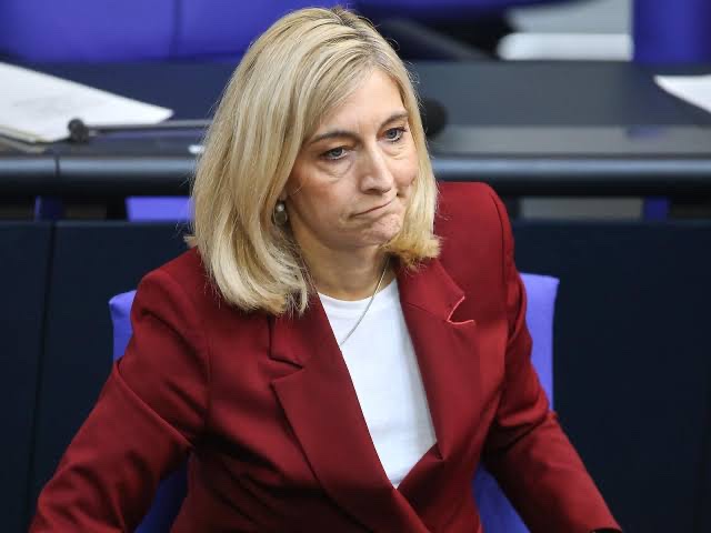 Nina Warken in a red jacket in the Bundestag plenary chamber
