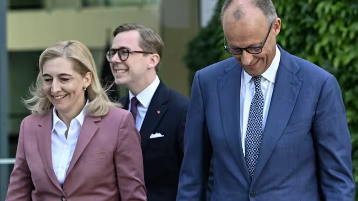Nina Warken walking beside Chancellor Friedrich Merz and Carsten Linnemann in Berlin on 24 July 2026