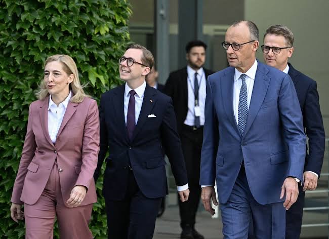 Nina Warken walking alongside Chancellor Friedrich Merz and other people